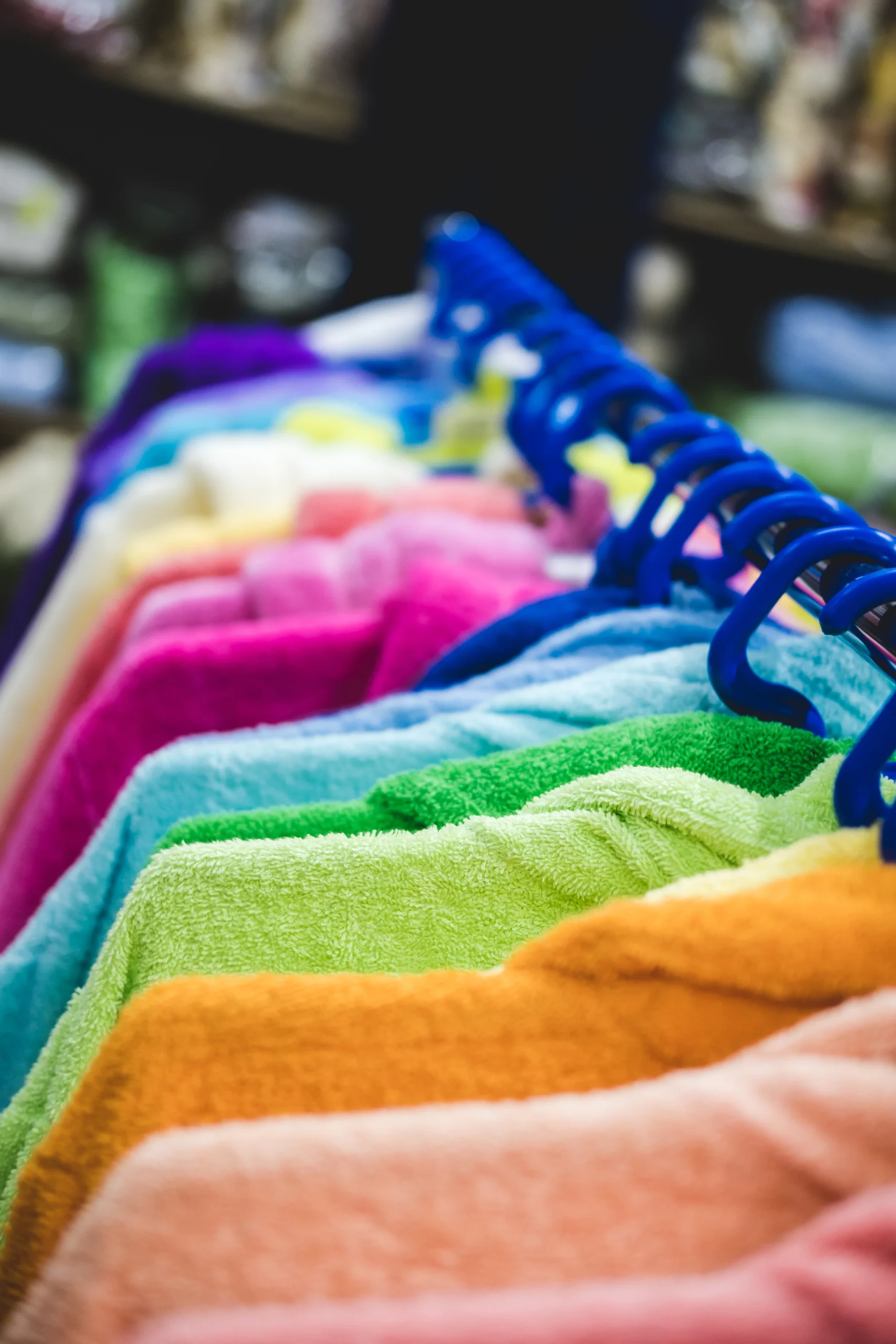 Multi-colored terry robes hanging in a row on hanger. 